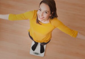 Woman smiling standing on a weighing scale